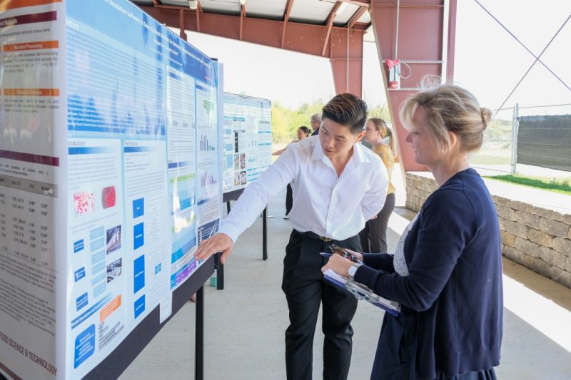 A student speaks to a judge about his poster during the annual FST Poster Competition