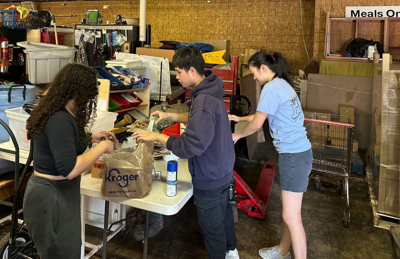 Students fill plastic grocery bags with food.