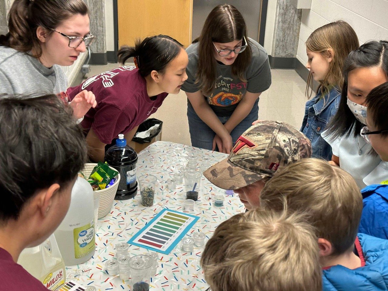 Students work with kids to conduct an experiment.