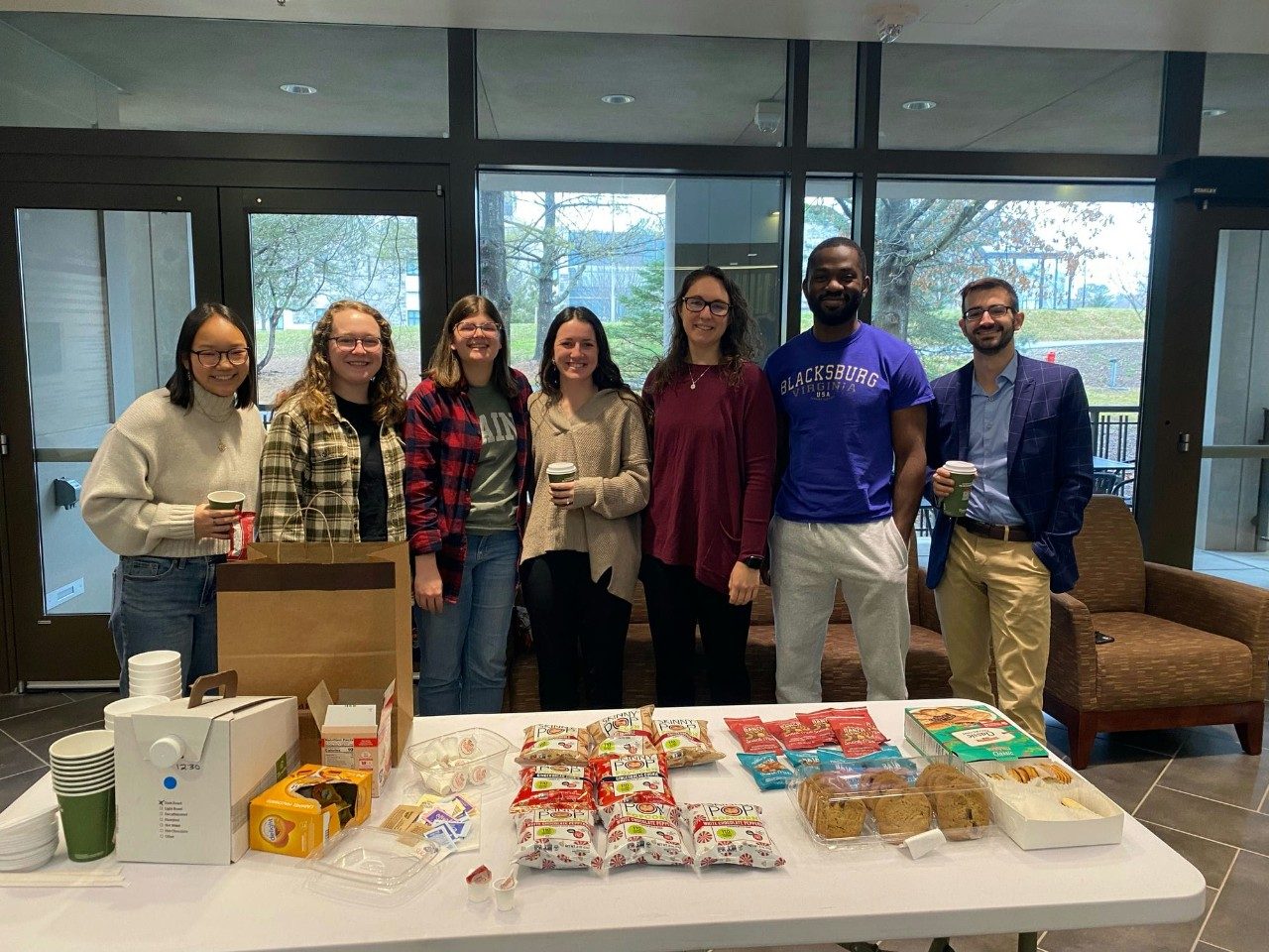 Students pose for a photo in front of a snack table.