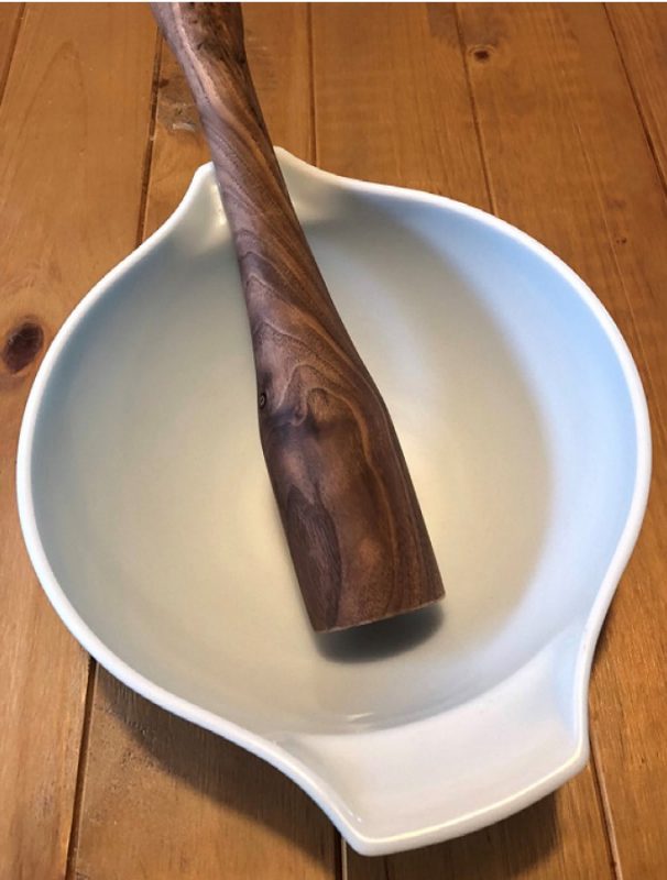 A small, wooden, bat-shaped tool sitting inside a white bowl.