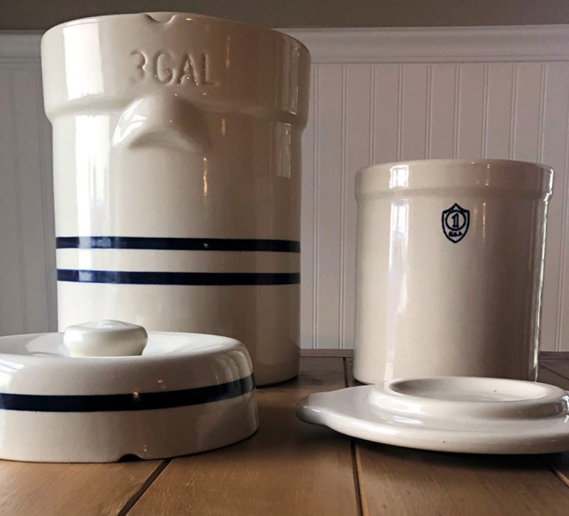 Two ceramic crocks. One is a large 3-gallon crock with lid, the other is a smaller 1-gallon crock with lid.
